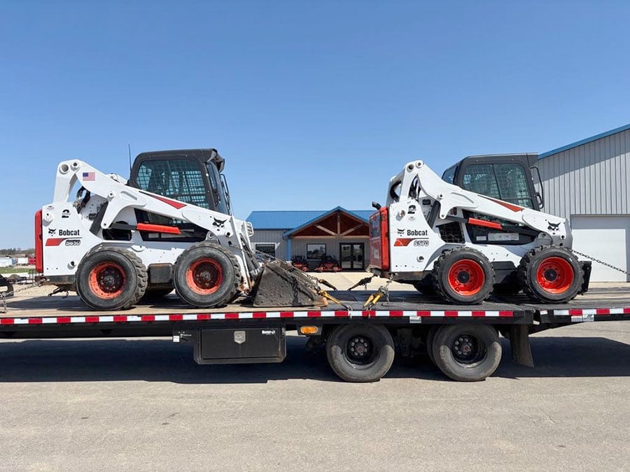 2 bobcat skidsteers on a trailer